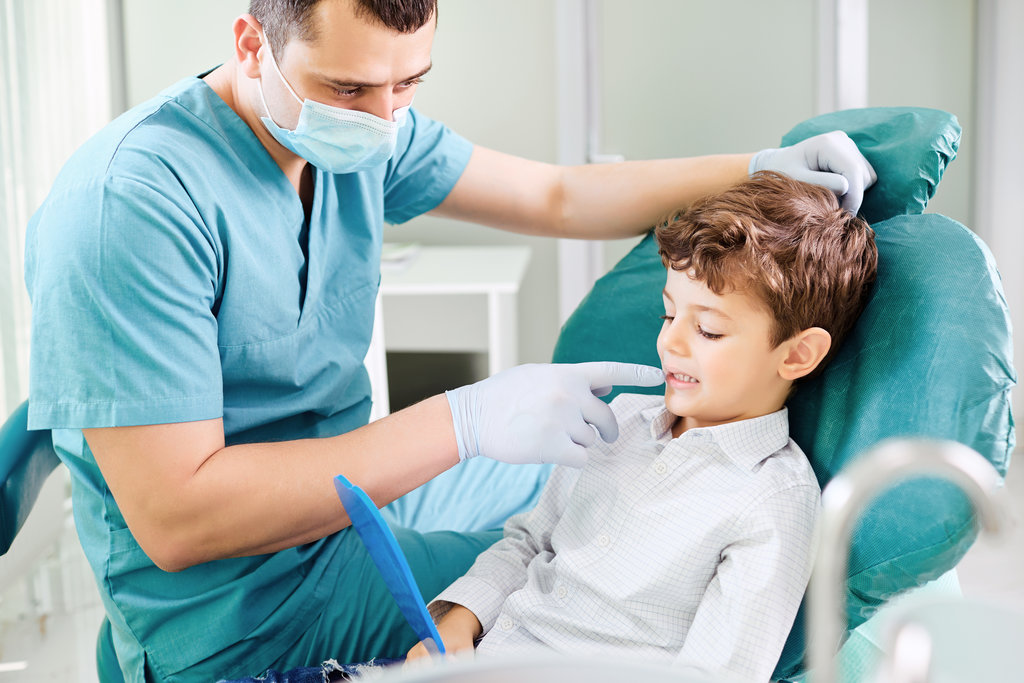 Boy child and dentist are checking teeth in the mirror in the dental clinic.